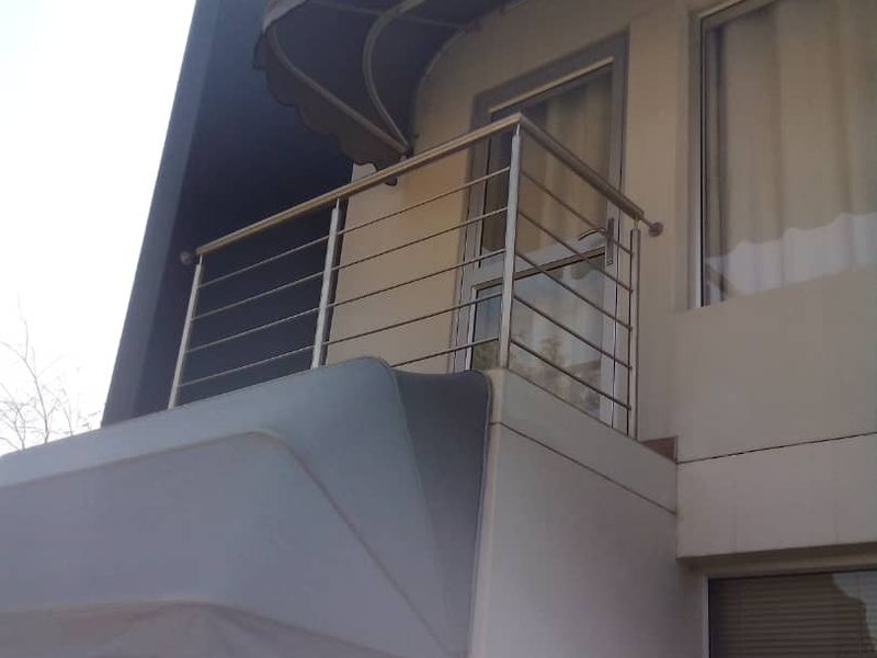 A private balcony featuring a modern stainless steel balustrade and a protective fabric awning, providing an outdoor extension to the upper level.