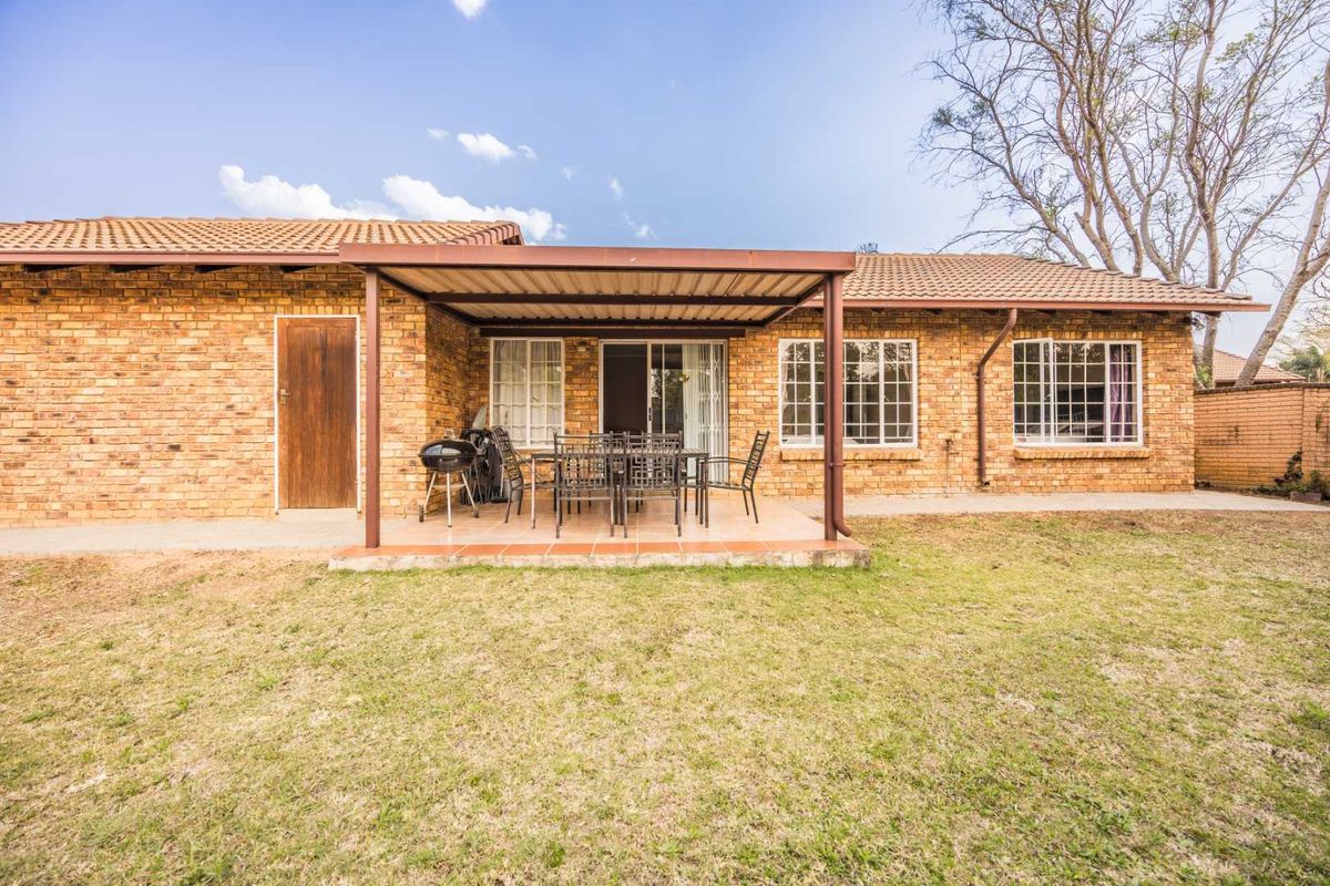 Rear view of the townhouse featuring a covered patio area, brick exterior, and access to the garden through sliding glass doors.