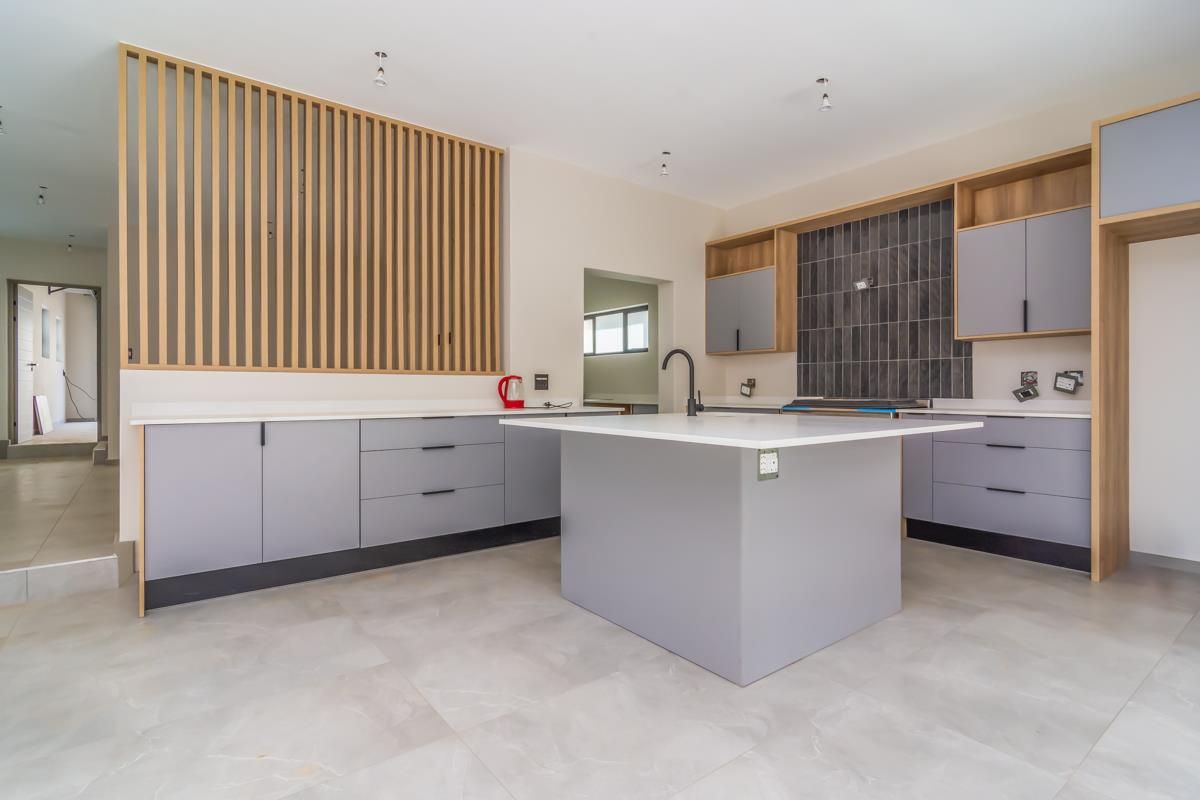 Modern kitchen featuring a central island, sleek grey cabinetry, timber slat feature wall, and tiled flooring in an open-plan layout.