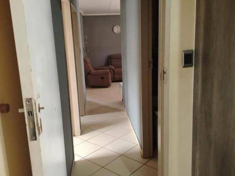 A functional hallway featuring tiled flooring and access to multiple rooms, showing signs of wear on the walls and door frames.