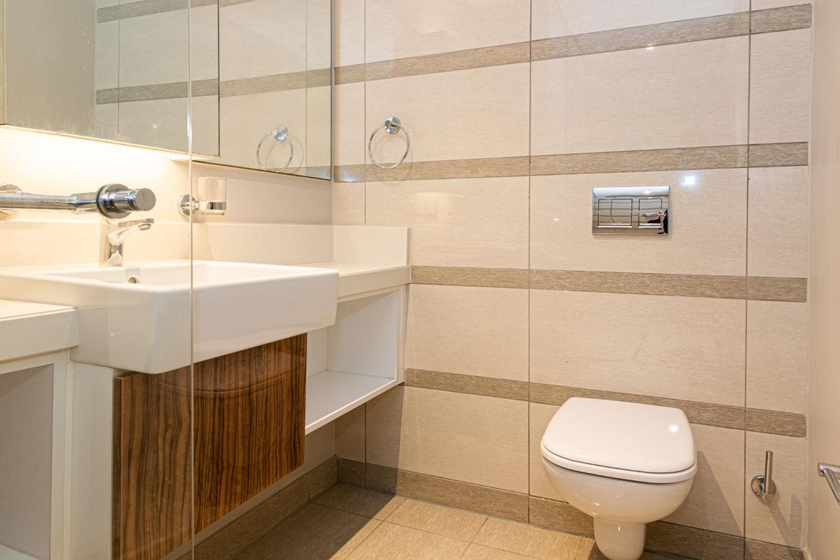 Modern bathroom featuring a wall-mounted toilet with concealed cistern, vanity basin with wall-mounted mixer, and neutral tiled finishes.