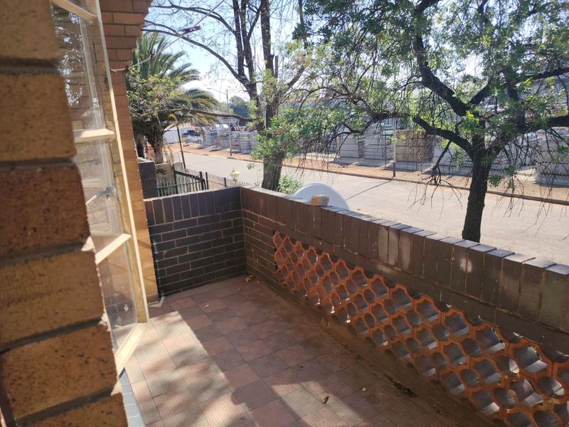 A private balcony featuring a brick balustrade with decorative breeze block detailing and tiled flooring, overlooking the street.