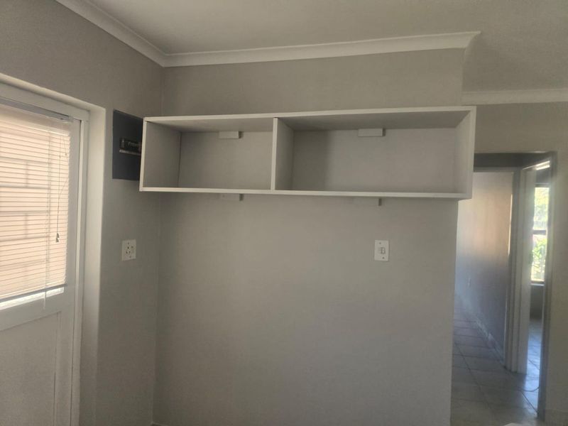 A utility area featuring built-in wall shelving, an electrical distribution board, and neutral wall finishes.