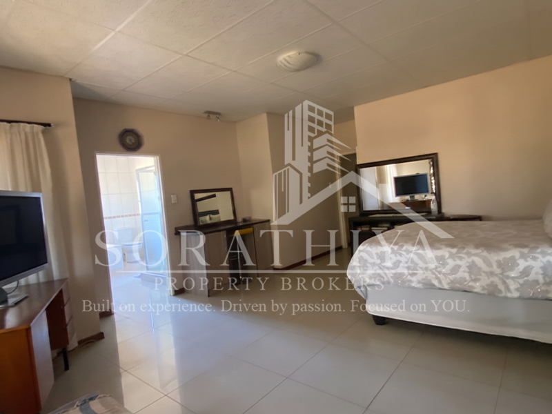 Spacious bedroom featuring tiled flooring, a built-in vanity, and direct access to an en-suite bathroom.