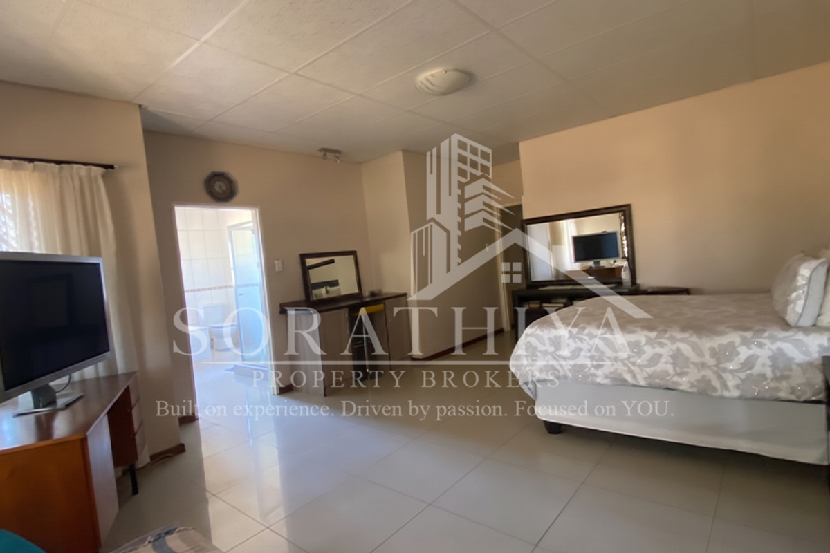 Spacious bedroom featuring tiled flooring, a built-in vanity, and direct access to an en-suite bathroom.