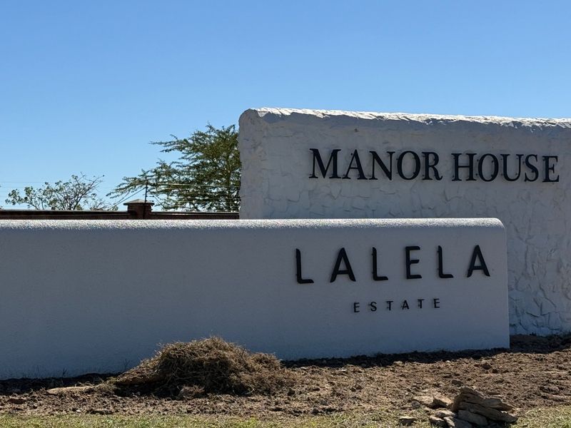 A clear view of the Lalela Estate Manor House entrance signage and surrounding boundary wall.