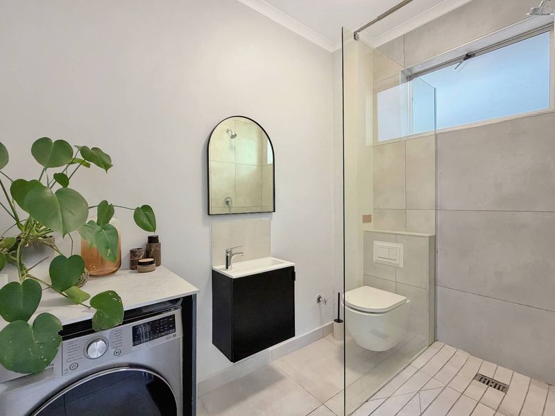 Modern bathroom featuring a wall-hung toilet with concealed cistern, a sleek wall-mounted vanity, and a spacious walk-in shower with a glass screen.