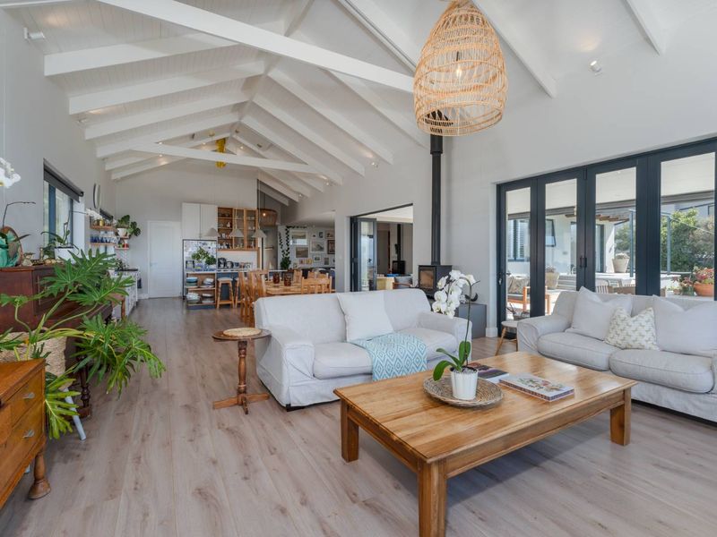 Spacious open-plan living area featuring vaulted ceilings with exposed beams, a wood-burning fireplace, and large bi-fold doors leading to the outdoor space.
