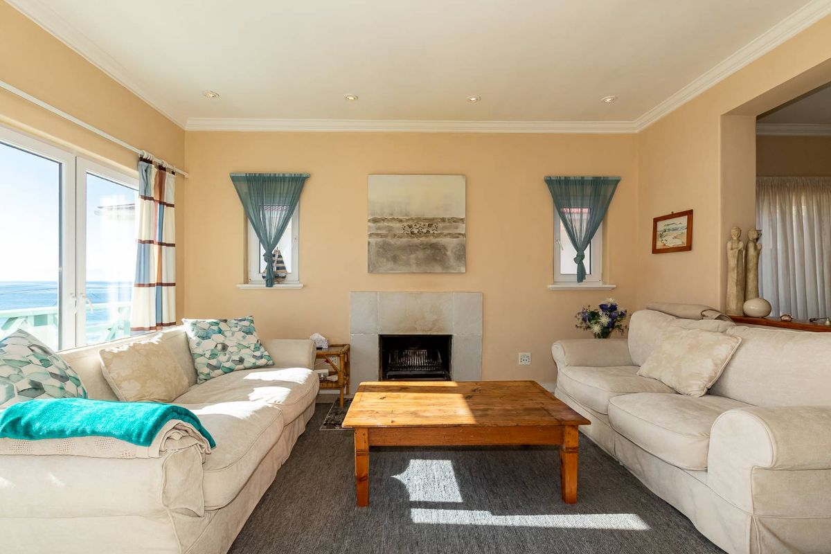A comfortable living room featuring a built-in fireplace, recessed ceiling lighting, and large windows offering natural light and ocean views.