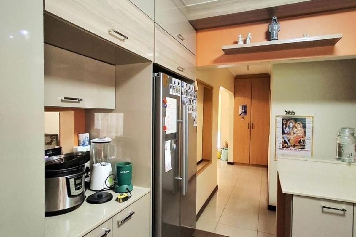 A functional kitchen featuring modern built-in cabinetry, stone countertops, and tiled flooring, leading into a hallway area.