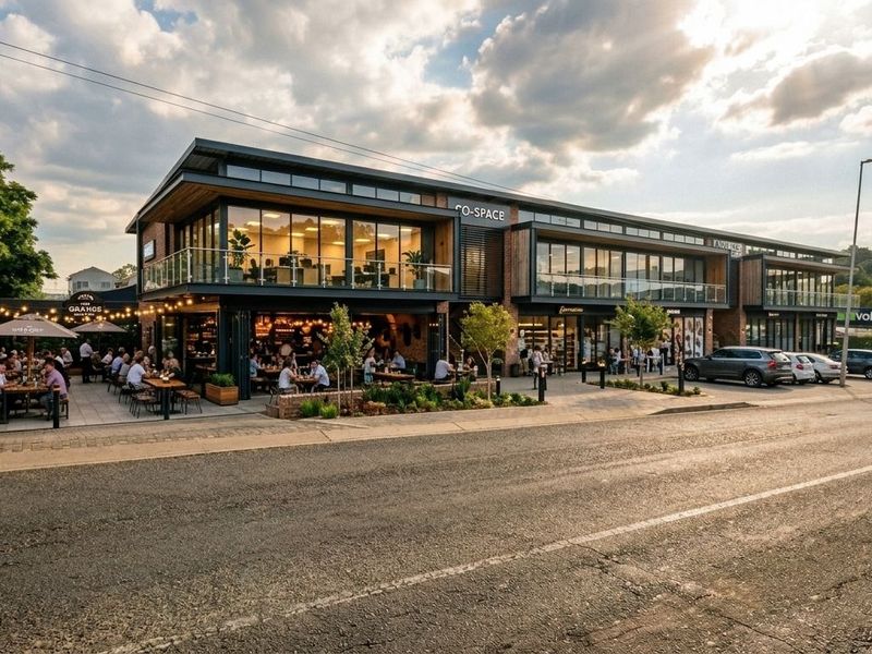 Modern mixed-use commercial building featuring a glass facade, balcony levels, and an integrated ground-floor patio area with street-level parking.
