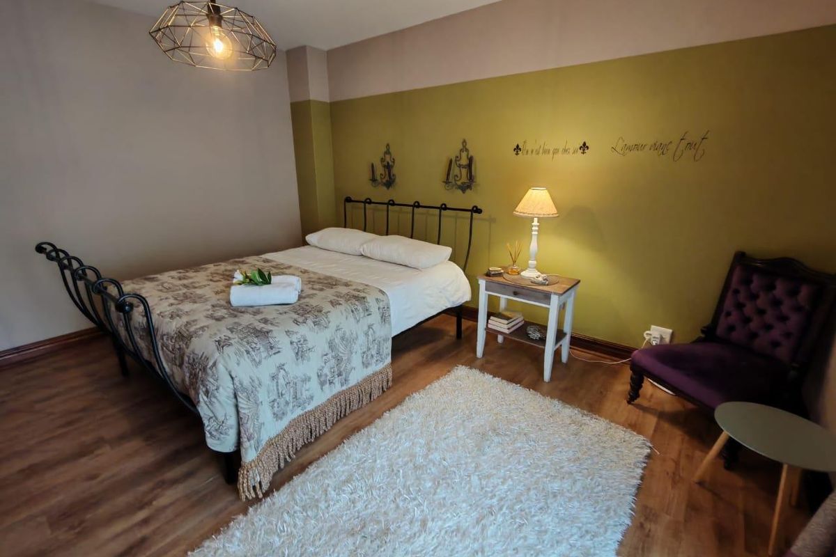 A well-maintained bedroom featuring laminate flooring, a modern pendant light fixture, and a two-tone painted wall finish.