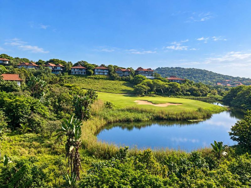 A scenic elevated view overlooking a lush golf course, tranquil lake, and surrounding residential estate landscape.