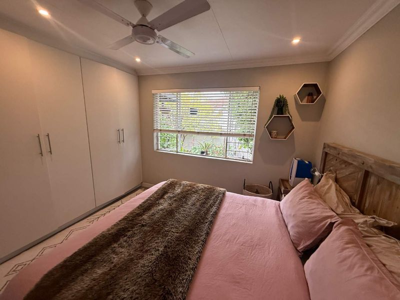 A well-maintained bedroom featuring built-in cupboards, a ceiling fan, recessed lighting, and venetian blinds, offering a comfortable and functional living space.