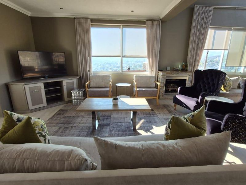 Spacious living room featuring a fireplace, large windows with panoramic views, recessed lighting, and light-toned laminate flooring.