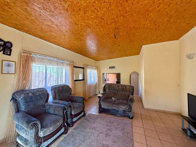A living room featuring tiled flooring and a distinctive wood-paneled ceiling, offering a functional space with potential for modern updates.