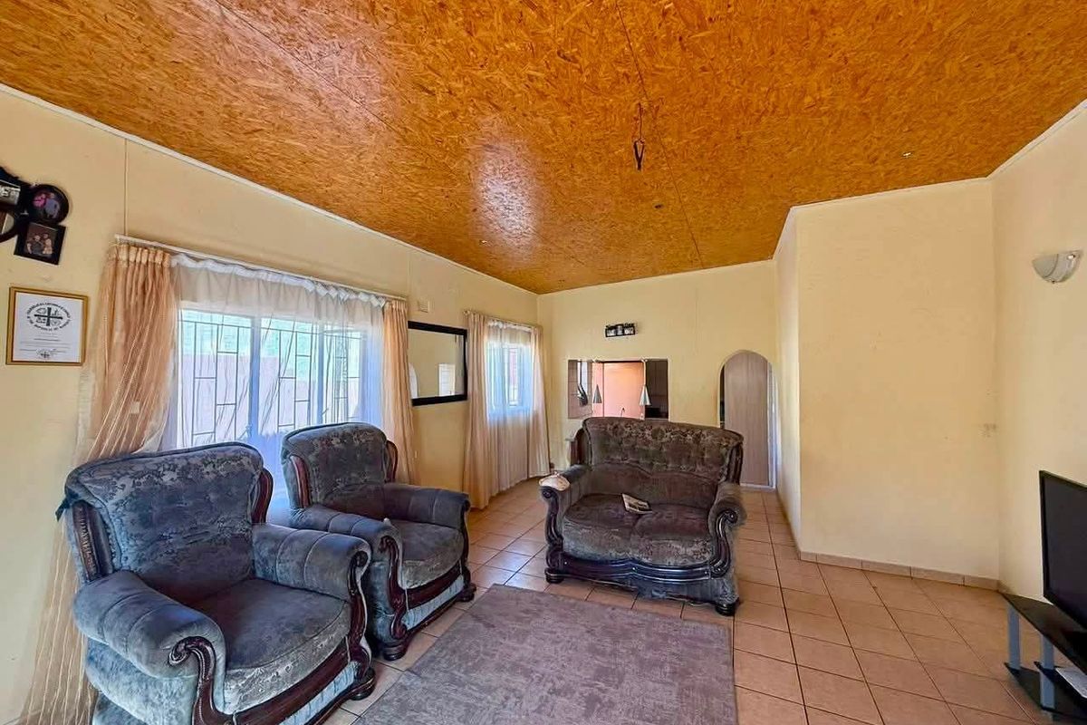 A living room featuring tiled flooring and a distinctive wood-paneled ceiling, offering a functional space with potential for modern updates.