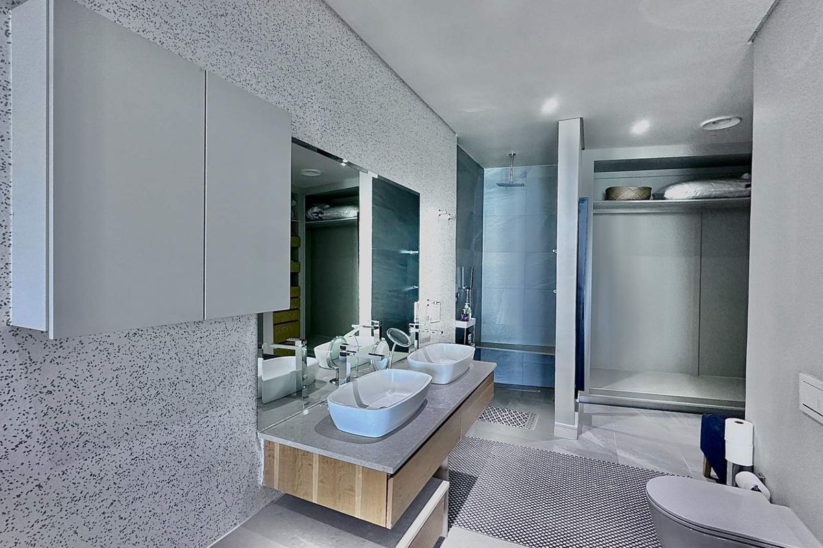 Modern bathroom featuring a floating double vanity with vessel sinks, a large mirror, and a spacious walk-in shower with integrated shelving.
