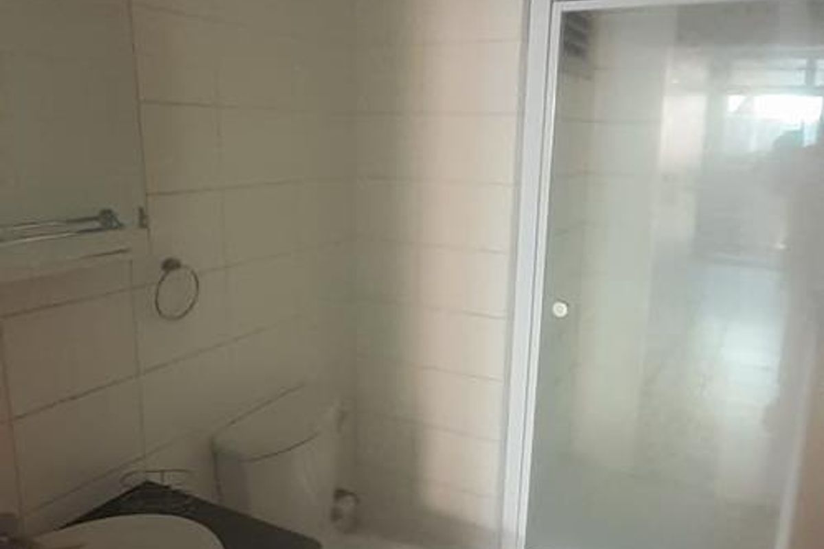 A functional bathroom featuring a vanity cabinet, toilet, and a glass-enclosed shower with tiled finishes throughout.