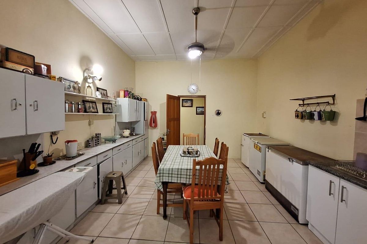 Spacious kitchen and dining area featuring extensive built-in cabinetry, tiled flooring, and a central ceiling fan, offering a functional layout for family meals.