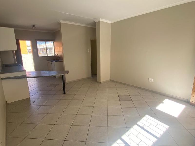 Open plan living and kitchen area featuring tiled flooring, built-in cabinetry, and a breakfast bar, offering a functional and versatile living space.