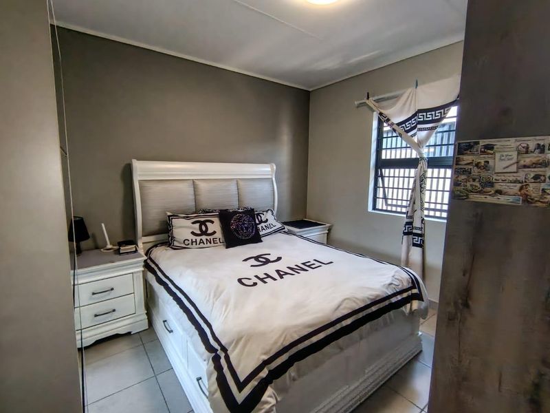 A functional bedroom featuring tiled flooring and a window fitted with security bars, offering a neutral base for personalization.