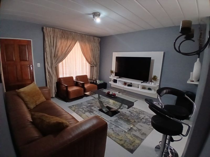 A comfortable living room featuring a built-in media console, tiled flooring, and a panelled ceiling, providing a functional and inviting space.