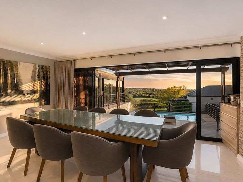 Elegant dining room featuring large sliding glass doors that open to a patio with pool and scenic landscape views.