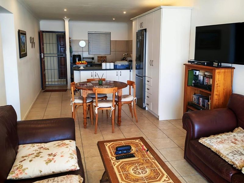 Open-plan living and dining area featuring tiled flooring, recessed lighting, and a functional kitchen space with built-in cabinetry.