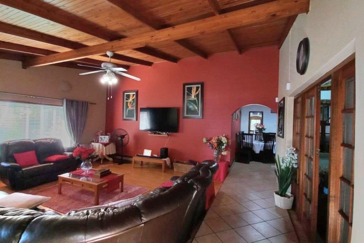 Spacious living area featuring a high exposed timber beam ceiling, tiled and laminate flooring, and an archway leading to the dining space.