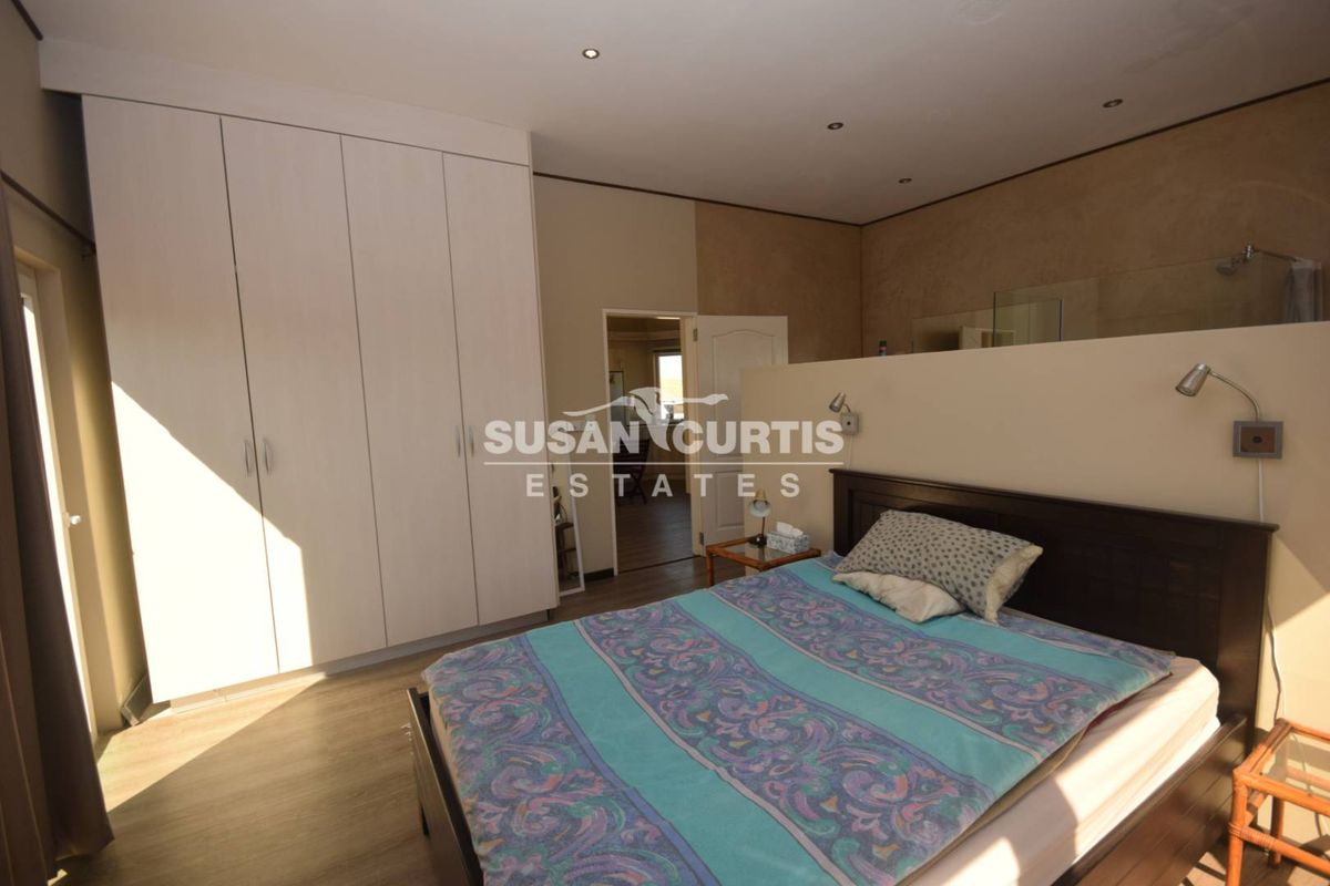 A bedroom featuring built-in wardrobes, recessed ceiling lighting, and an open-plan layout with an integrated en-suite bathroom area.