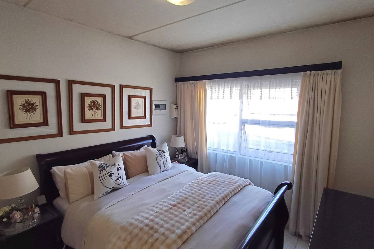 A cozy bedroom featuring a large window with curtain tracks and neutral wall finishes.