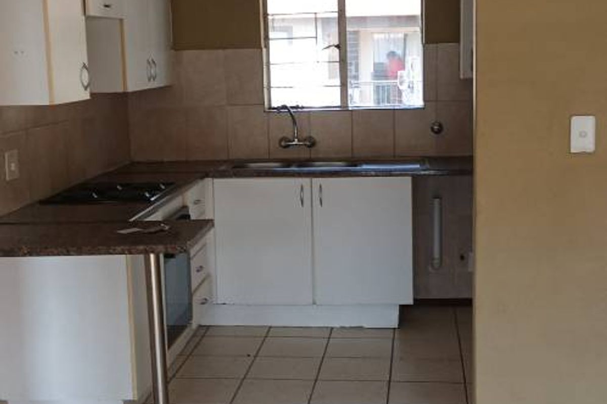 A functional kitchen featuring built-in cabinetry, laminate countertops, a stainless steel sink, and tiled flooring, offering a clean and practical workspace.