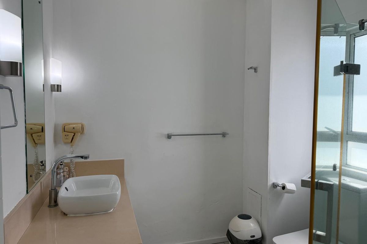 A functional bathroom featuring a modern vessel sink, vanity countertop, wall-mounted mirror, and a glass-enclosed shower area.