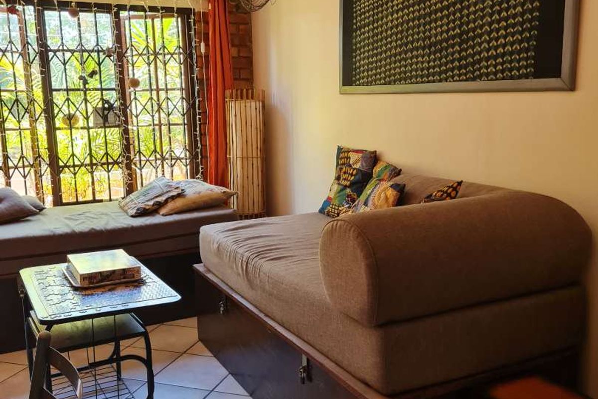 A living area featuring tiled flooring, a brick accent wall, and large sliding glass doors with security bars leading to an outdoor space.