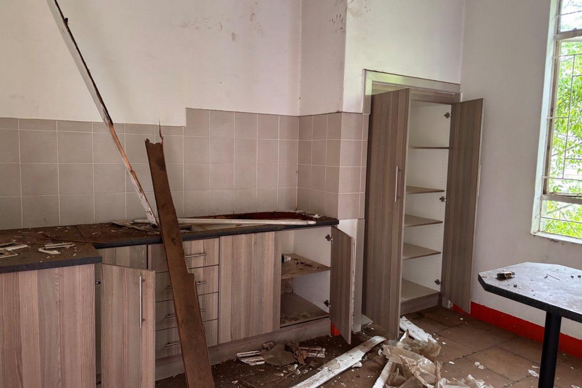 A damaged kitchen area featuring built-in cabinetry and tiled splashbacks, currently in need of significant repair and renovation.