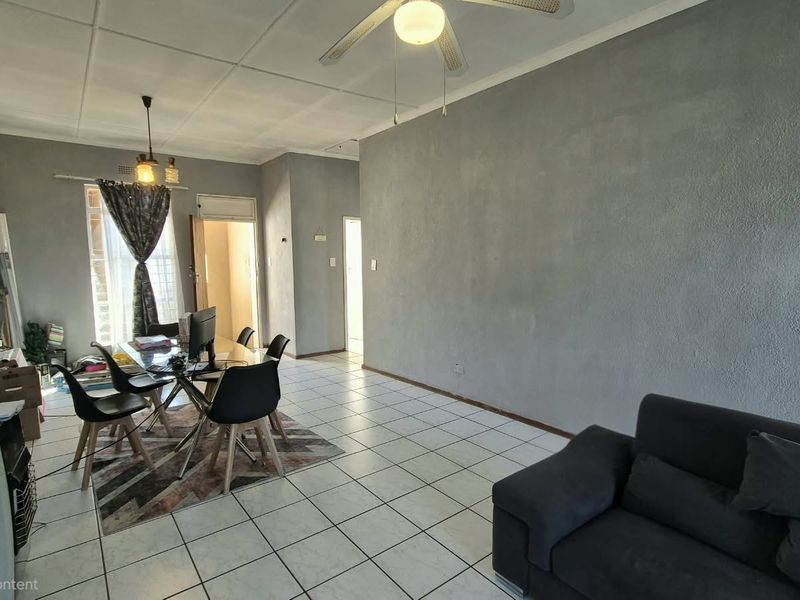 Open-plan living and dining area featuring tiled flooring, a ceiling fan, and textured wall finishes.