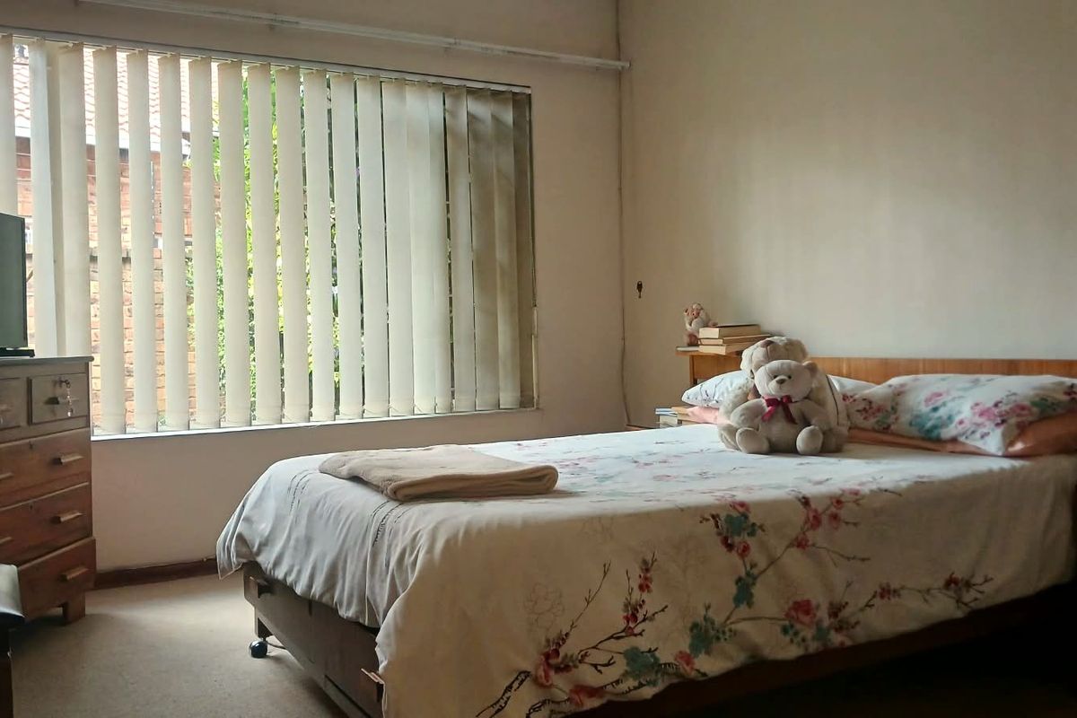 A bedroom featuring carpet flooring and vertical blinds, requiring cosmetic updates to improve the overall aesthetic and condition of the space.
