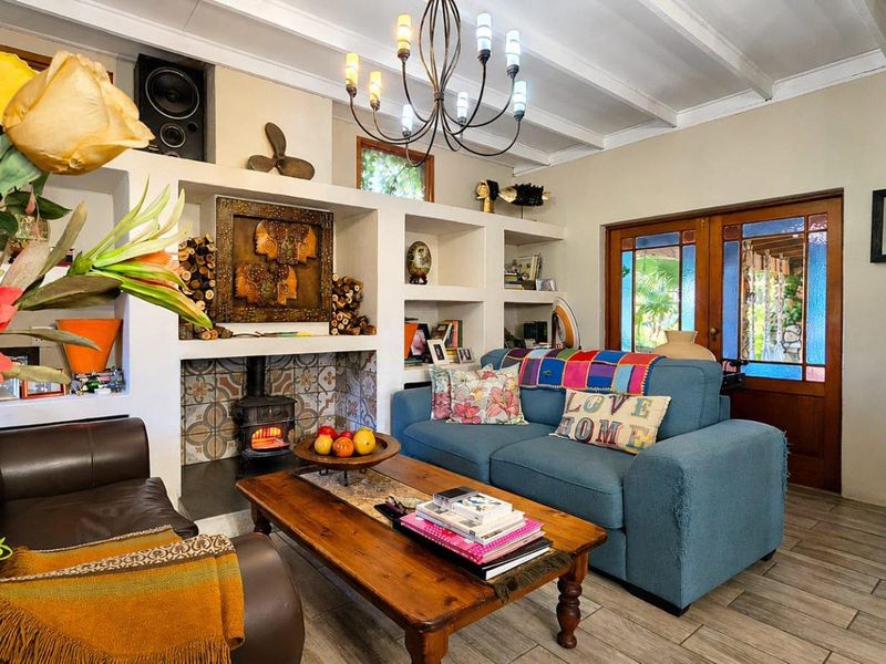 Cozy living room featuring a built-in fireplace with decorative tiling, exposed beam ceilings, and direct access to the outdoor area through wooden glass doors.