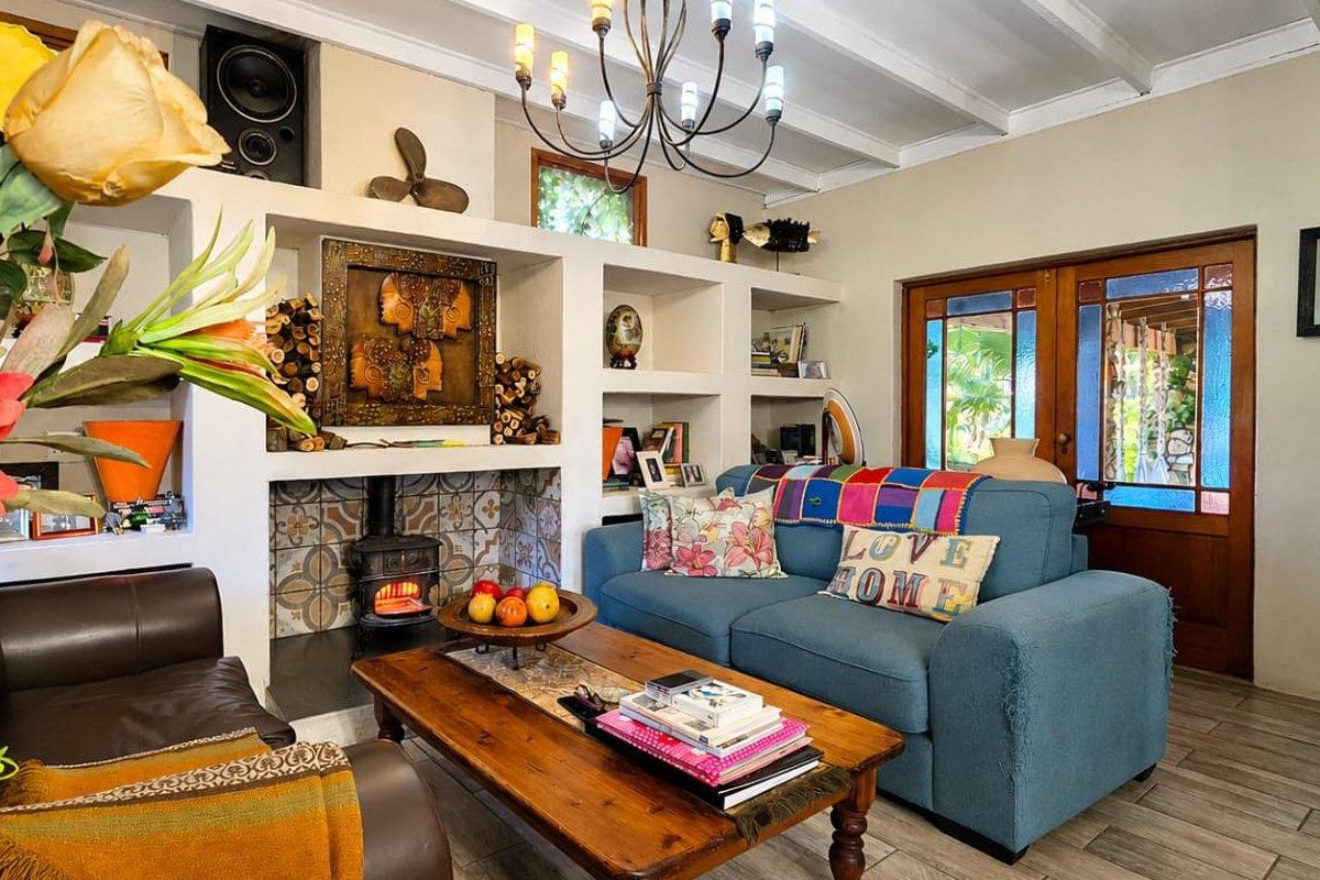 Cozy living room featuring a built-in fireplace with decorative tiling, exposed beam ceilings, and direct access to the outdoor area through wooden glass doors.