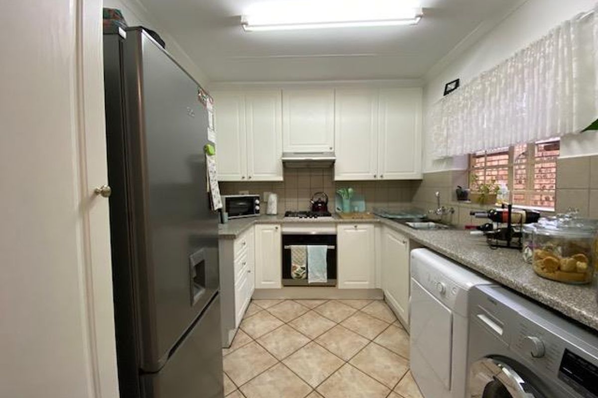 Functional kitchen featuring white cabinetry, stone-look countertops, tiled flooring, and integrated cooking appliances, providing a practical workspace.