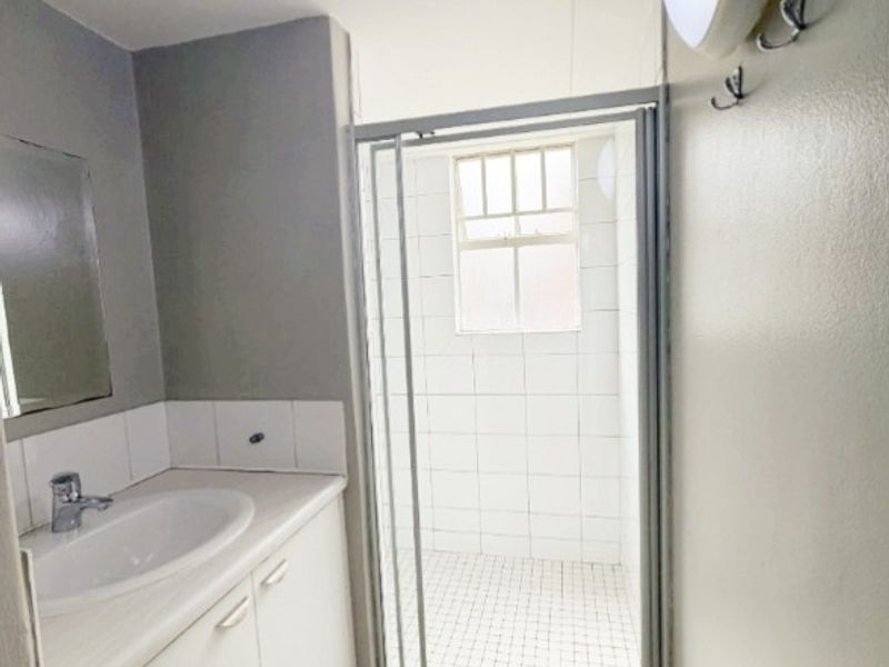 A functional bathroom featuring a vanity with basin, a separate shower enclosure with tiled finishes, and neutral wall tones.