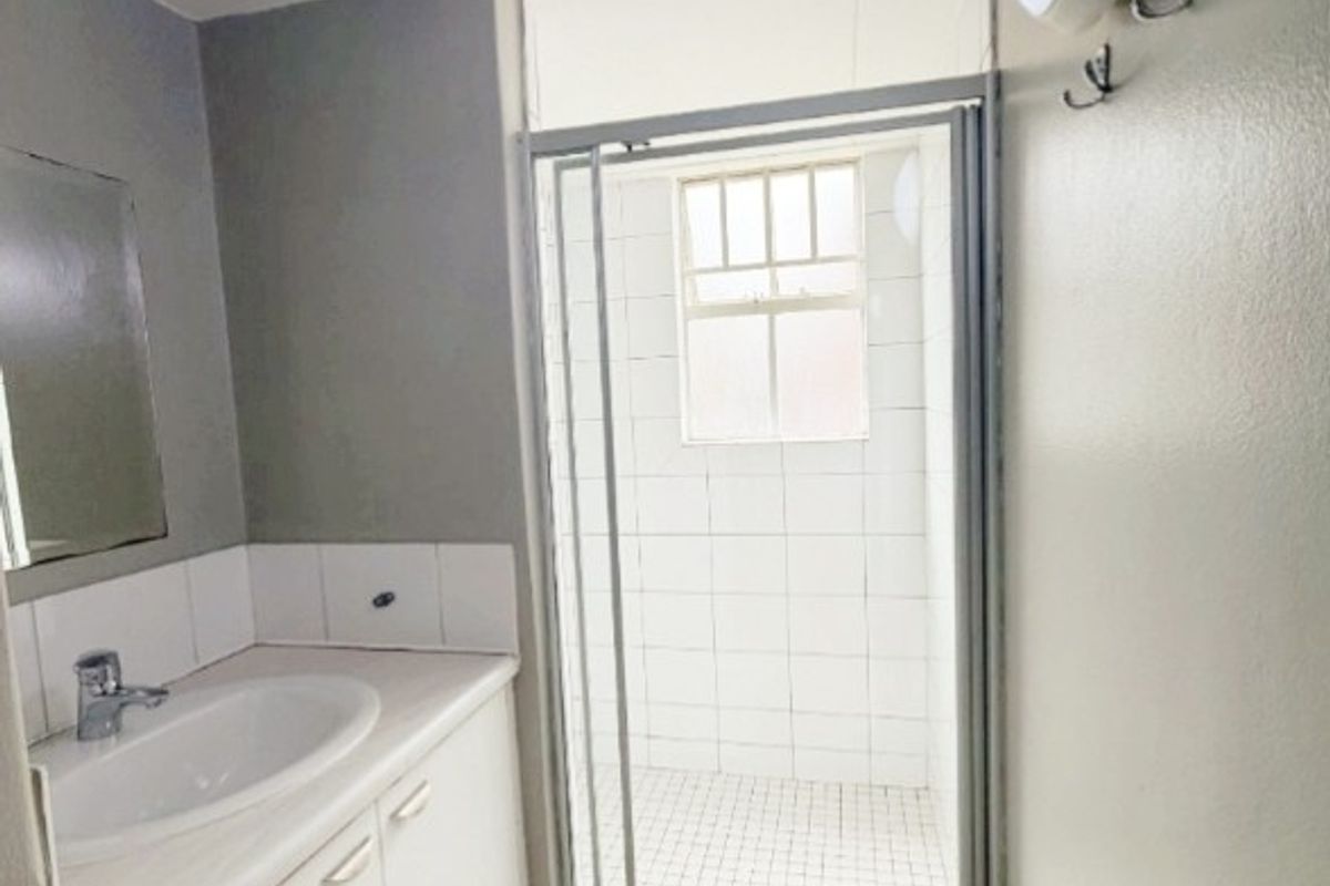 A functional bathroom featuring a vanity with basin, a separate shower enclosure with tiled finishes, and neutral wall tones.