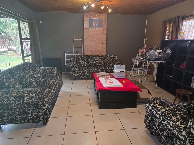 Spacious living room featuring tiled flooring, a timber ceiling, and a tiled feature wall with direct access to the garden through a sliding door.
