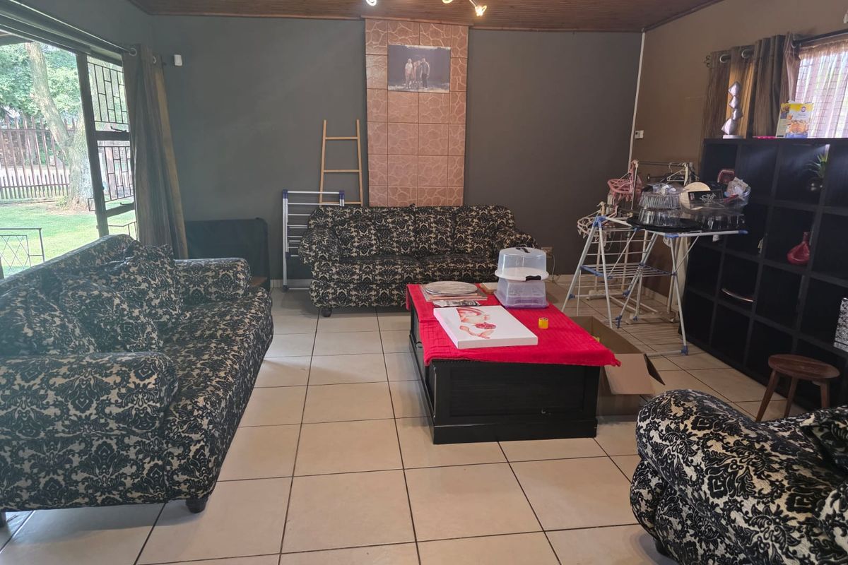 Spacious living room featuring tiled flooring, a timber ceiling, and a tiled feature wall with direct access to the garden through a sliding door.