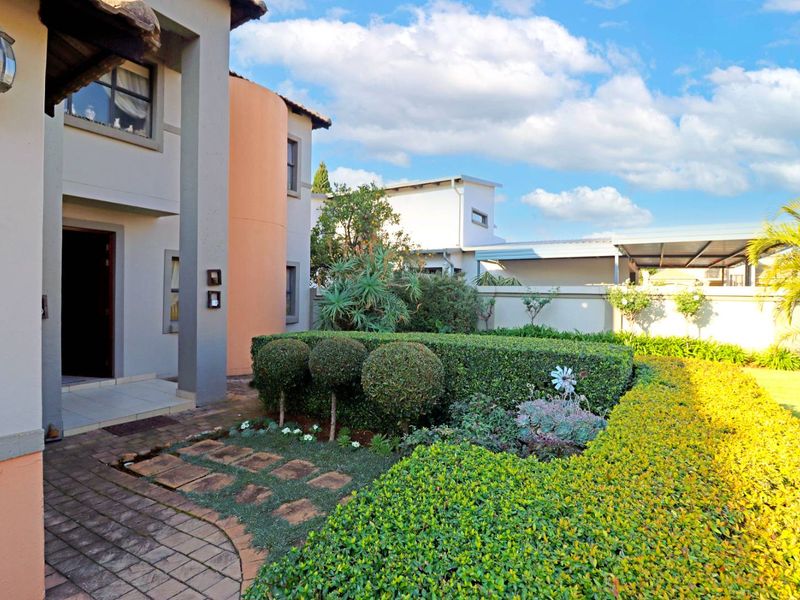 A well-maintained front entrance featuring a paved walkway, manicured hedges, and a covered porch area with exterior lighting.