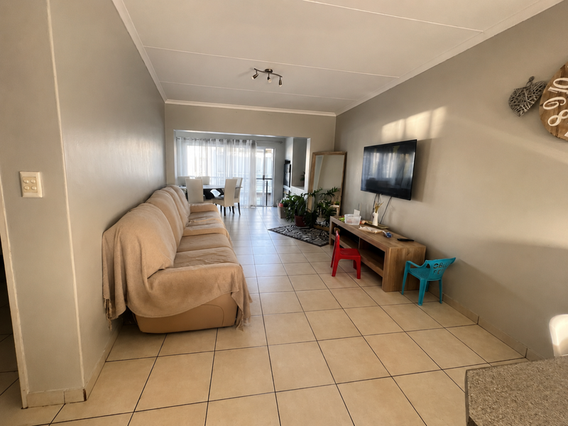 Open plan living area featuring neutral wall tones, ceramic floor tiles, and a sliding glass door leading to an outdoor space.
