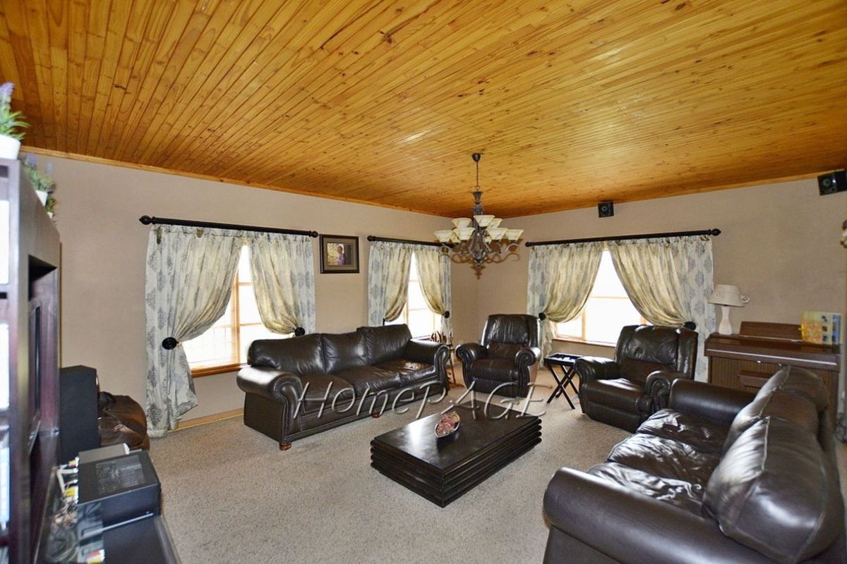 Spacious living room featuring a distinctive timber-clad ceiling, neutral wall tones, and multiple windows providing natural light.