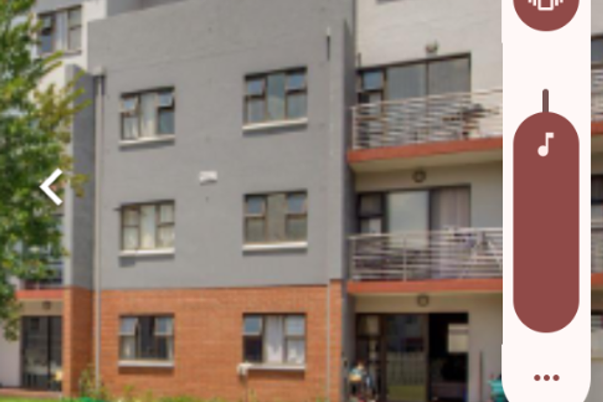 Exterior view of a multi-story apartment building featuring brick and plaster facade, balconies, and a well-maintained communal lawn area.