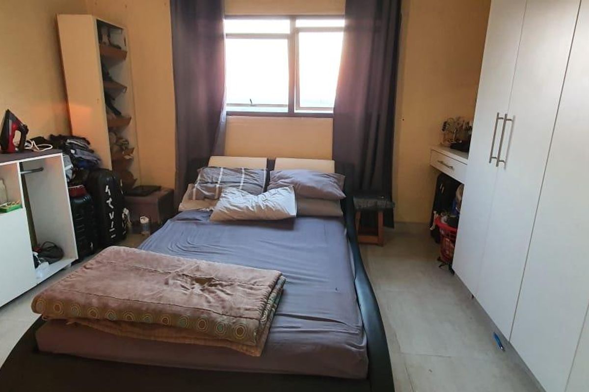 A functional bedroom featuring a built-in wardrobe and a window, providing natural light and storage space.